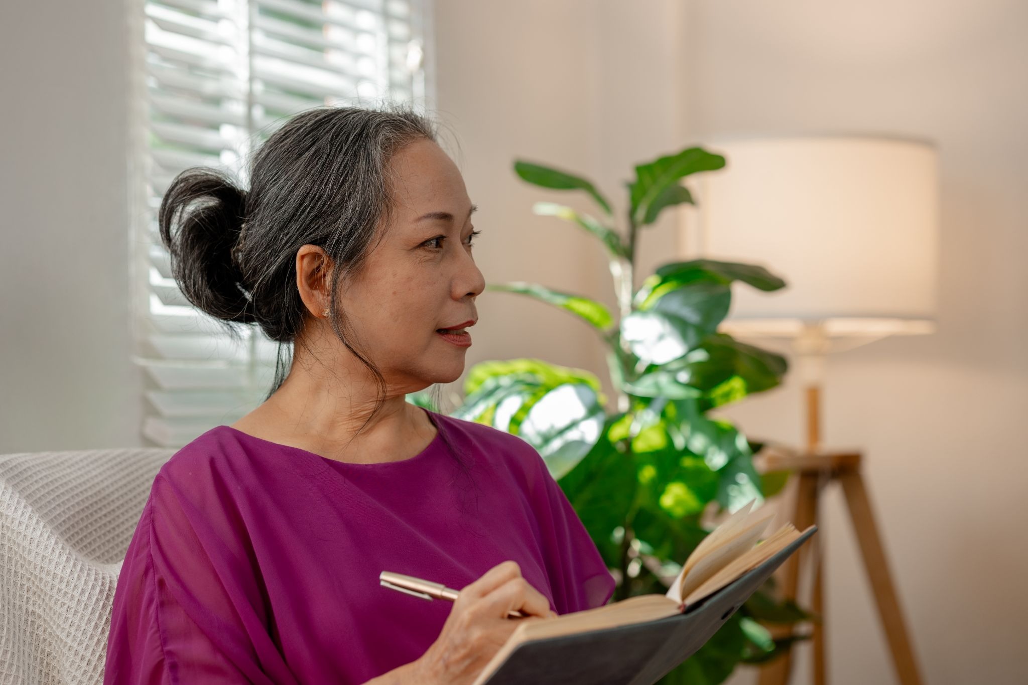  Caregiver reflecting and writing in a journal during the new year, representing thoughtful new year's resolutions and personal time for caregivers focused on balance and emotional well-being.