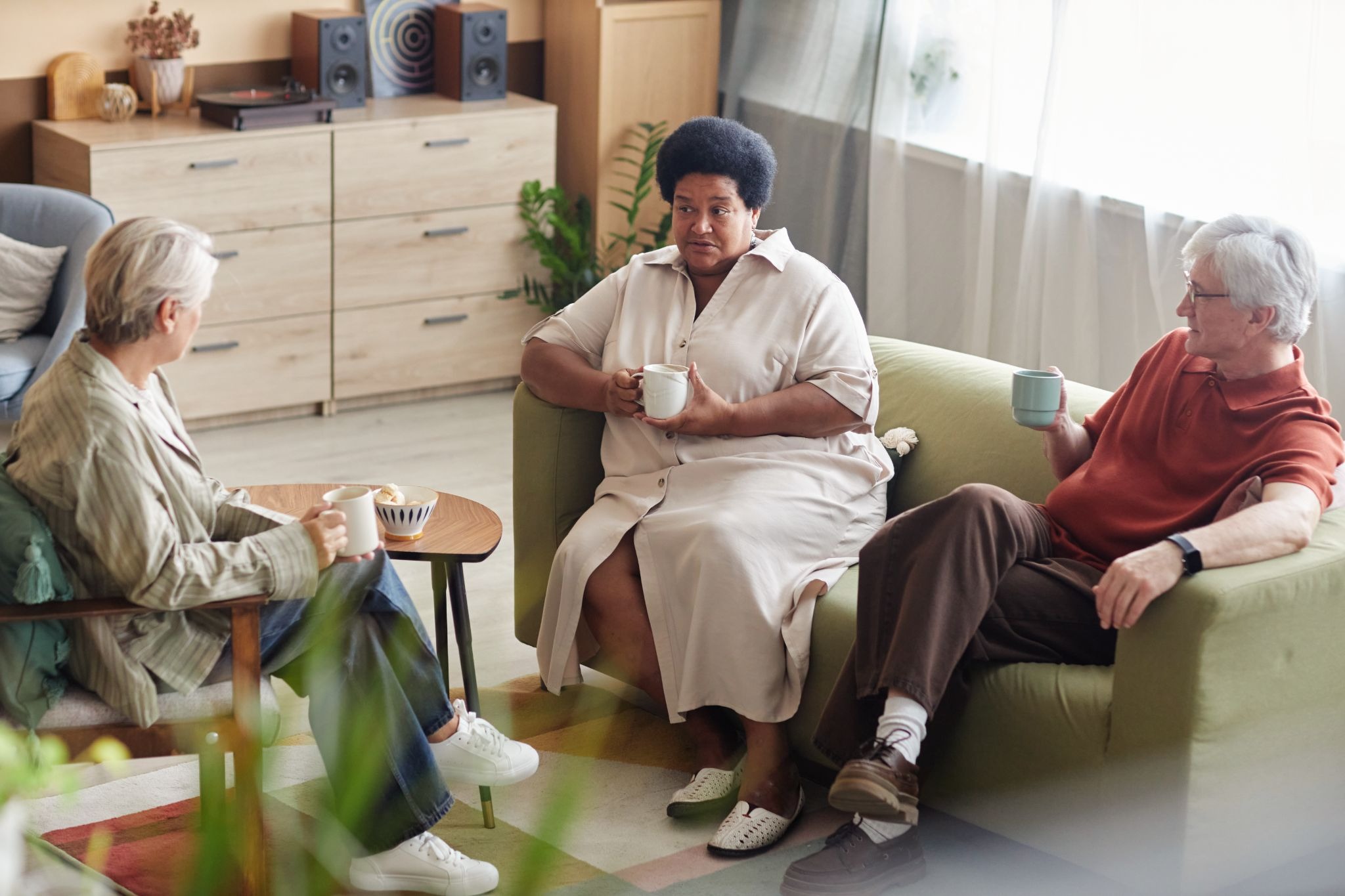 Older adults talking together in a shared living space at a medicaid nursing home, showing social connection and long-term care support.