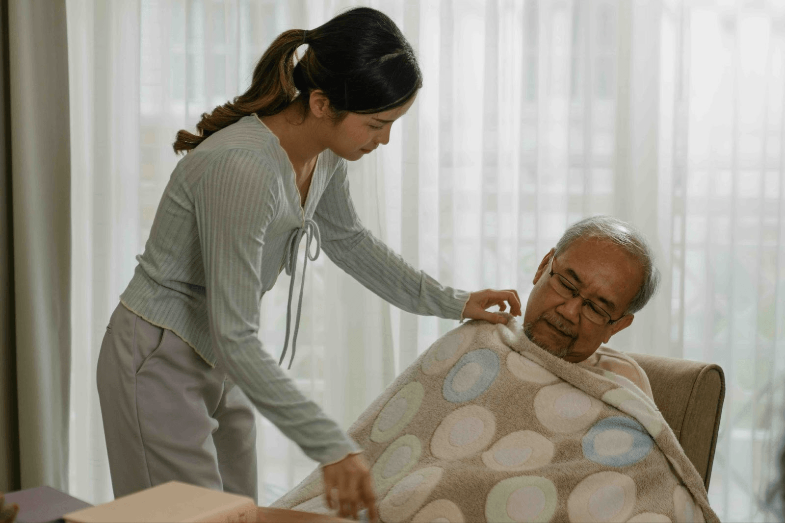 Young woman caring for her elderly father at home, showing the role of working caregivers balancing family caregiving while employed.