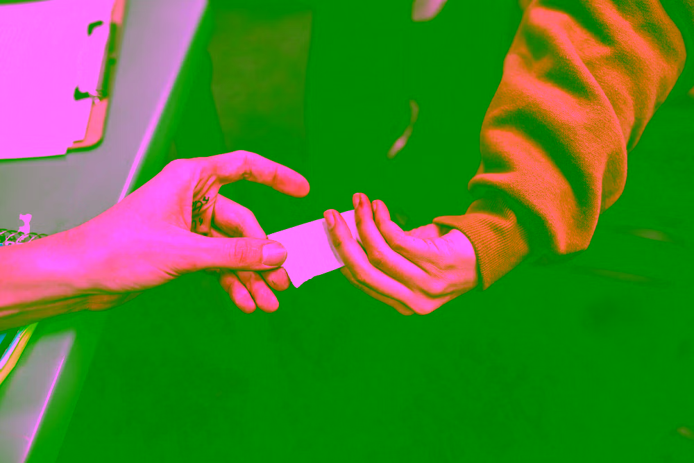 Une main d’homme et une main de femme qui s’échangent un message discret — la séduction qui s’exprime sans forcer.