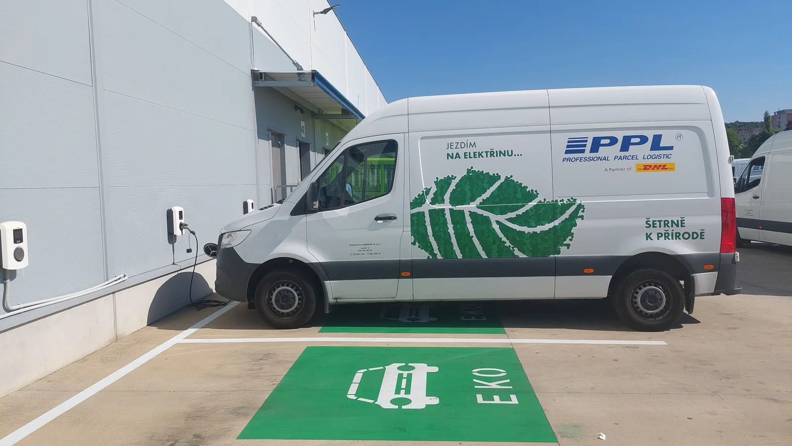 Elektrická dodávka PPL dobíjí u nástěnné dobíjecí stanice v depu