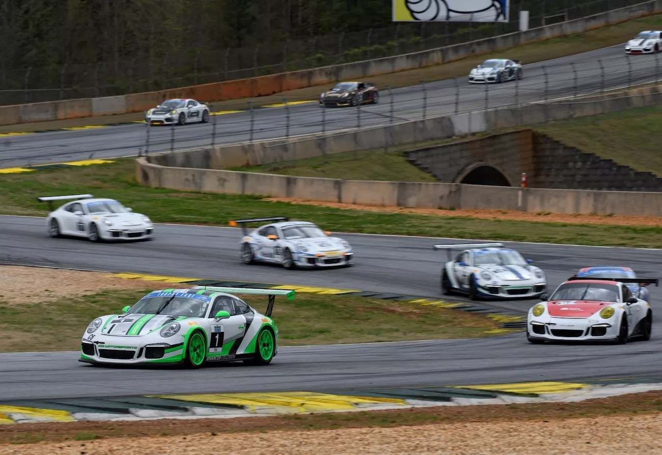 ACI Motorsports #1 green and white Porsche 911 GT3 Cup leading a pack of Porsches through a corner at Road Atlanta