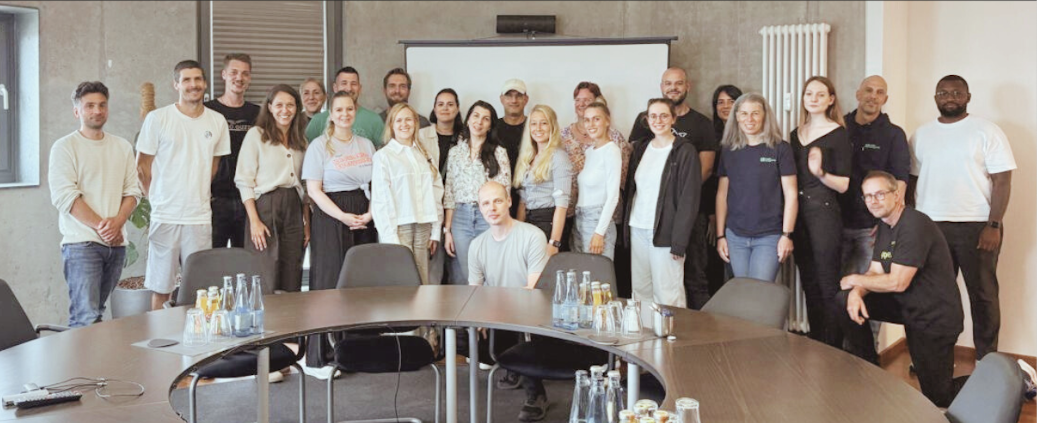 Group photo of Atlassian partners at the Hamburg Roundtable, gathered in a modern conference room around a circular table.