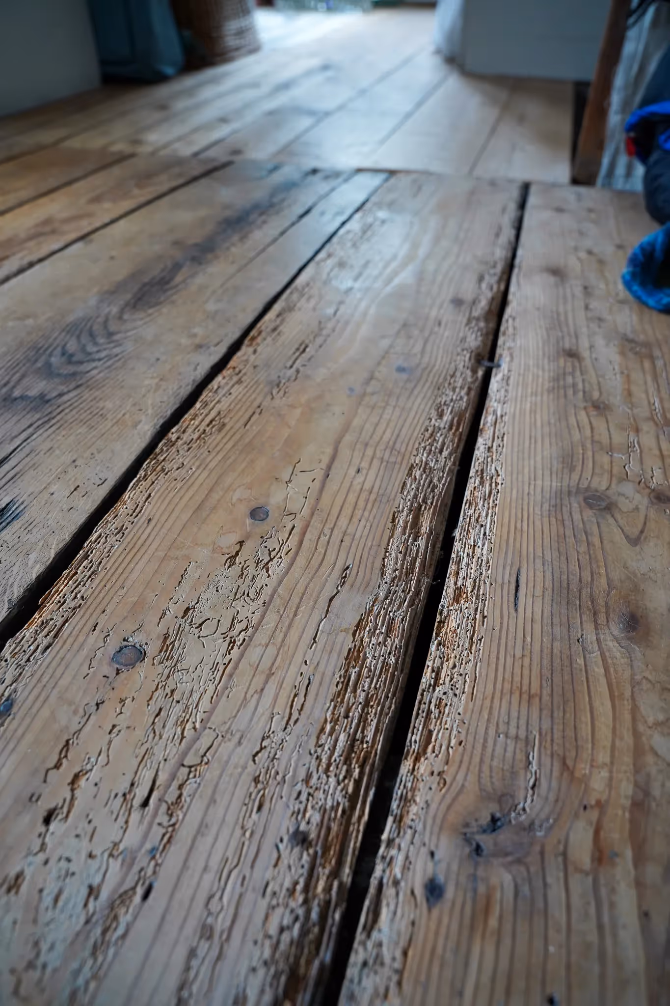 Nahaufnahme von verwittertem, altem Holzboden mit sichtbaren Rissen und Texturen.