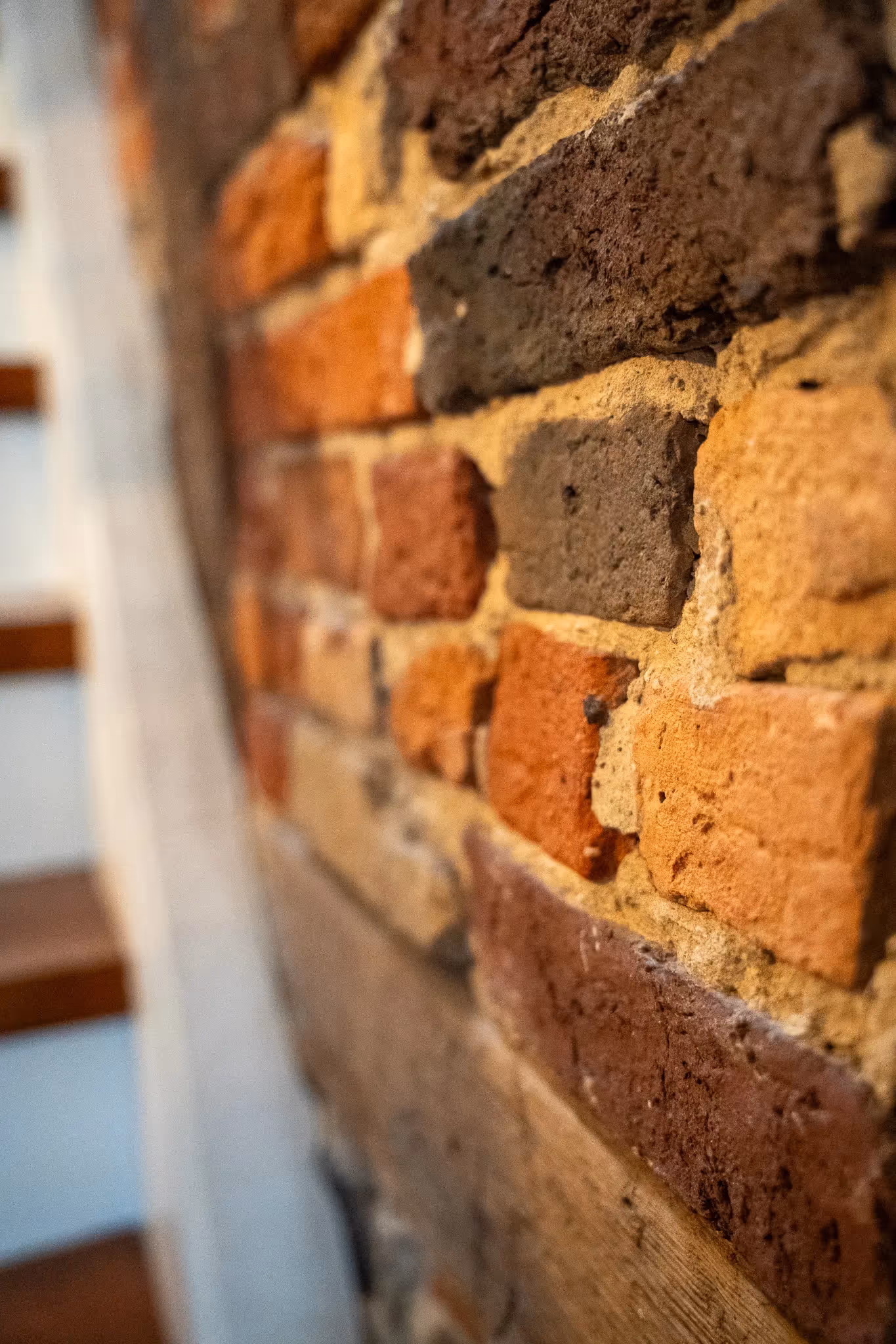 Nahaufnahme einer rustikalen Ziegelsteinmauer mit verschiedenen Erdfarben.