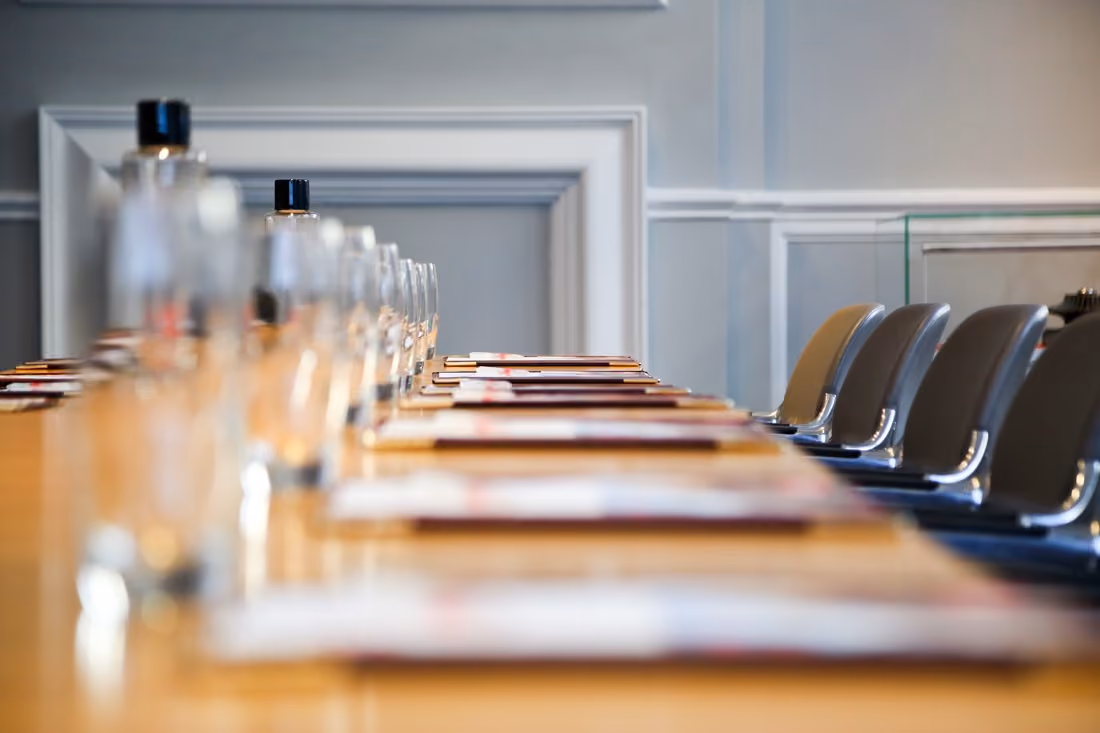 Long conference table with empty glasses, water bottles, and chairs in a meeting room.