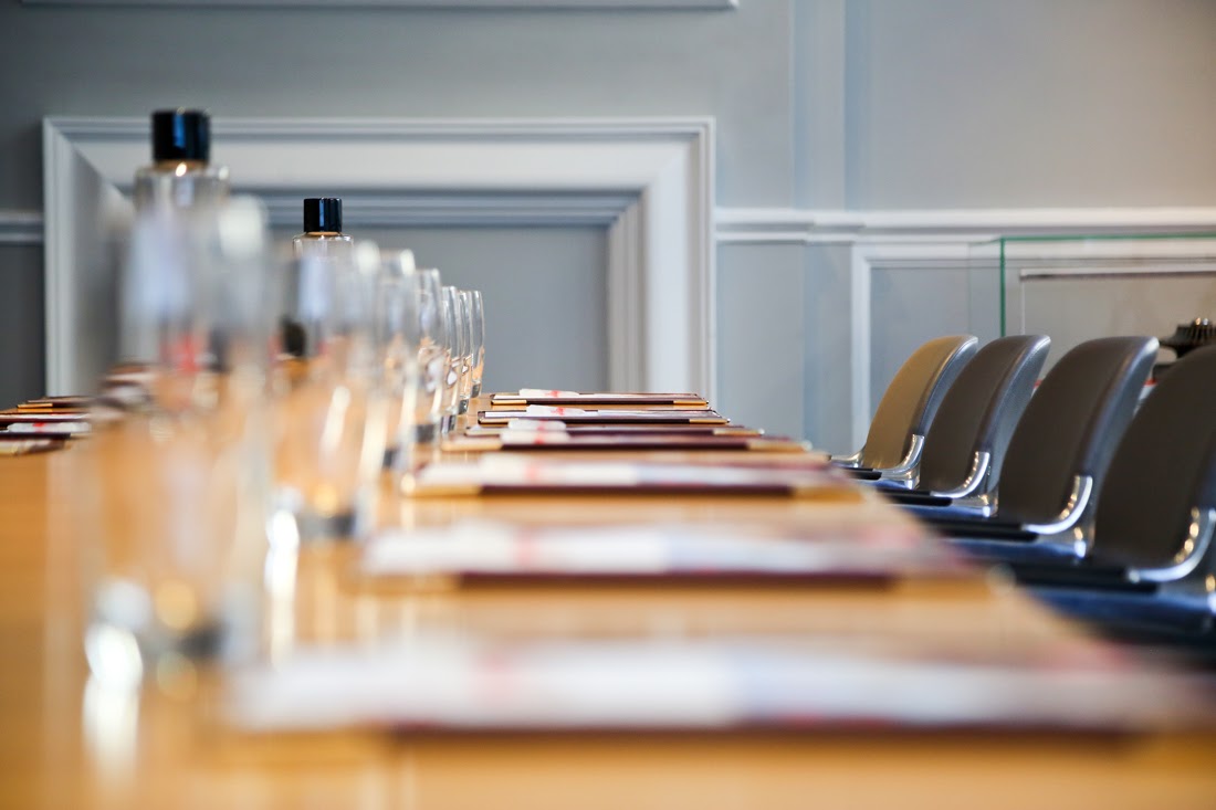 Long conference table with empty glasses, water bottles, and chairs in a meeting room.