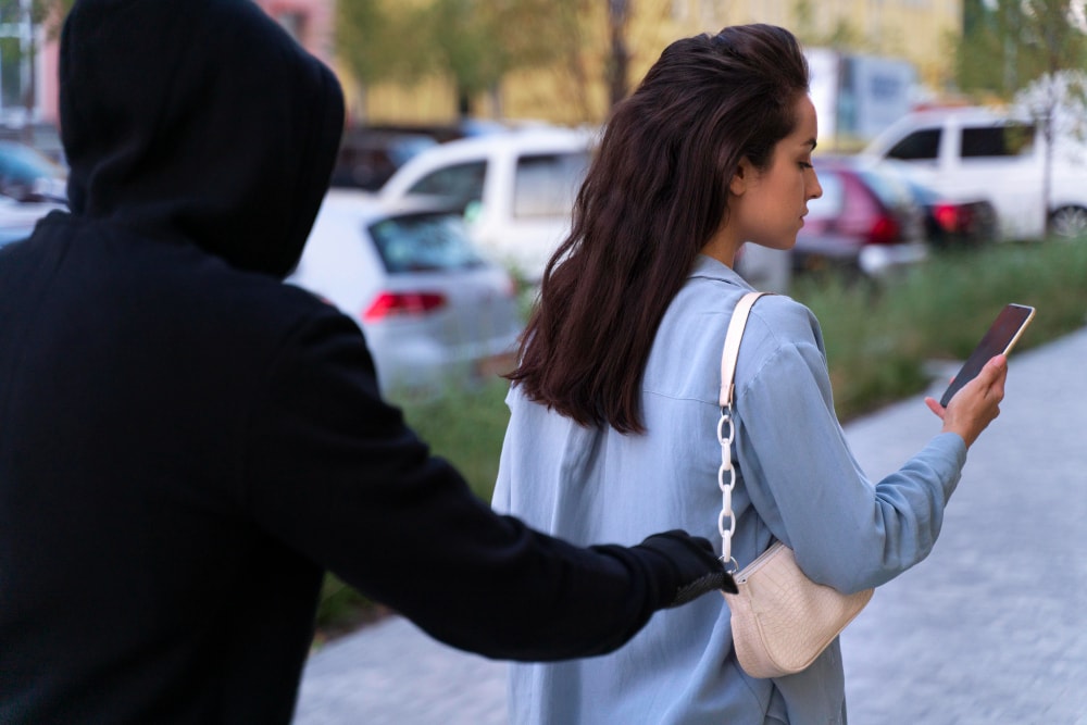 hooded man about to steal bag from unsuspecting woman