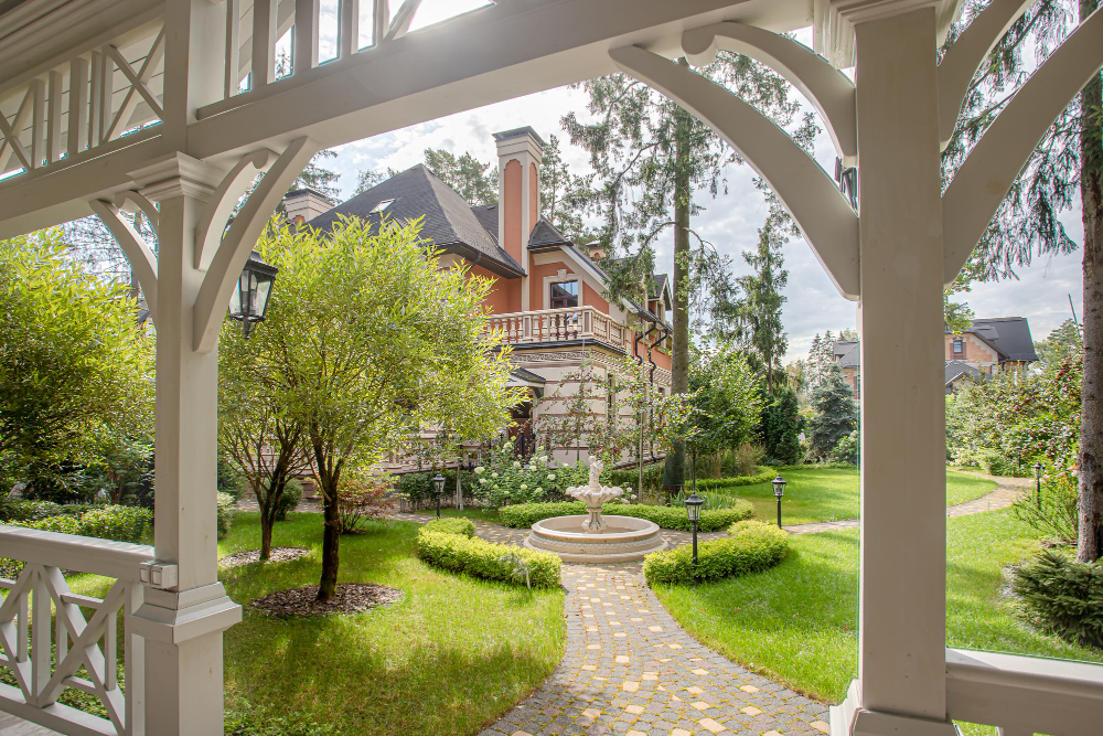 View of the house through a wooden white gazebo in the garden