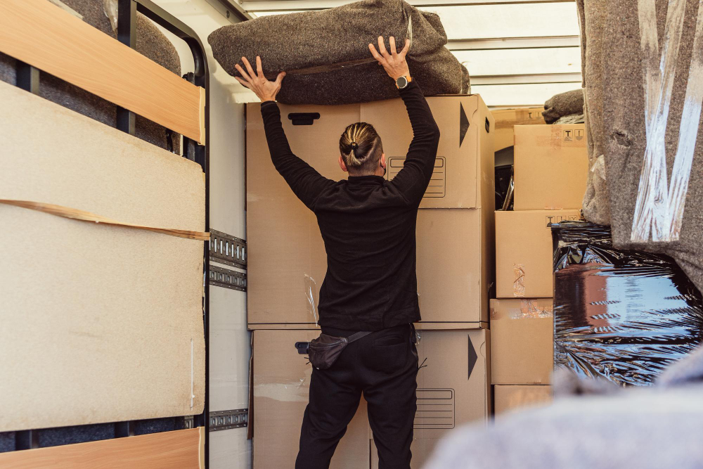 Worker with ponytail placing a bundle on top of cardboard boxes inside lorry