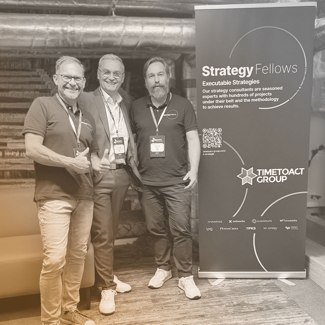3 Männer, darunter Harald Grabner, CEO von 123 Consulting, stehen neben einem Aufsteller von Strategy Fellows von TIMETOACT Group.