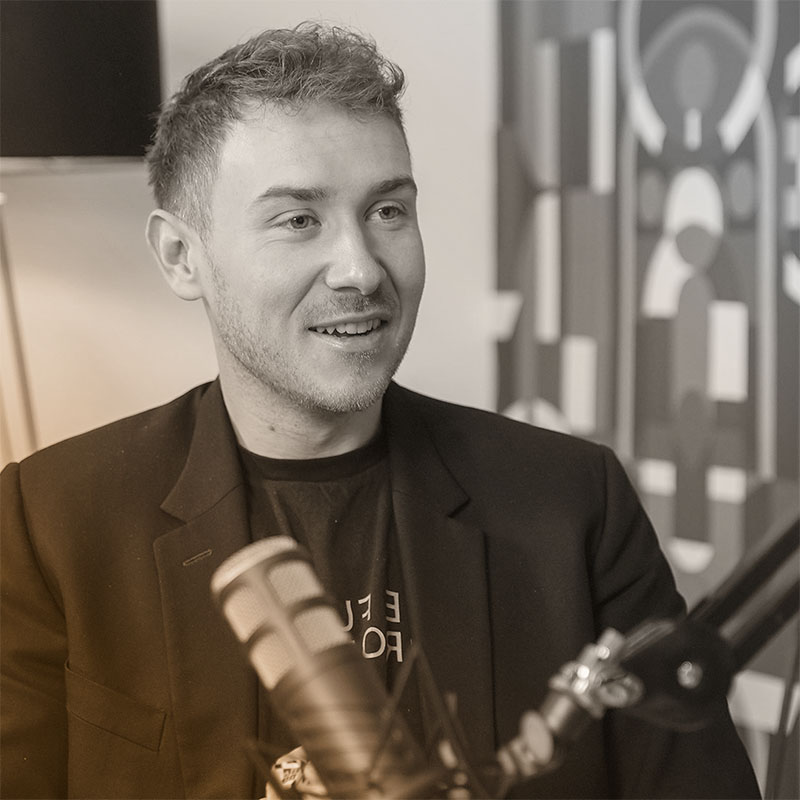 Junger Mann,Tristan Horx, mit kurzem Haar und Sakko spricht in ein Mikrofon.