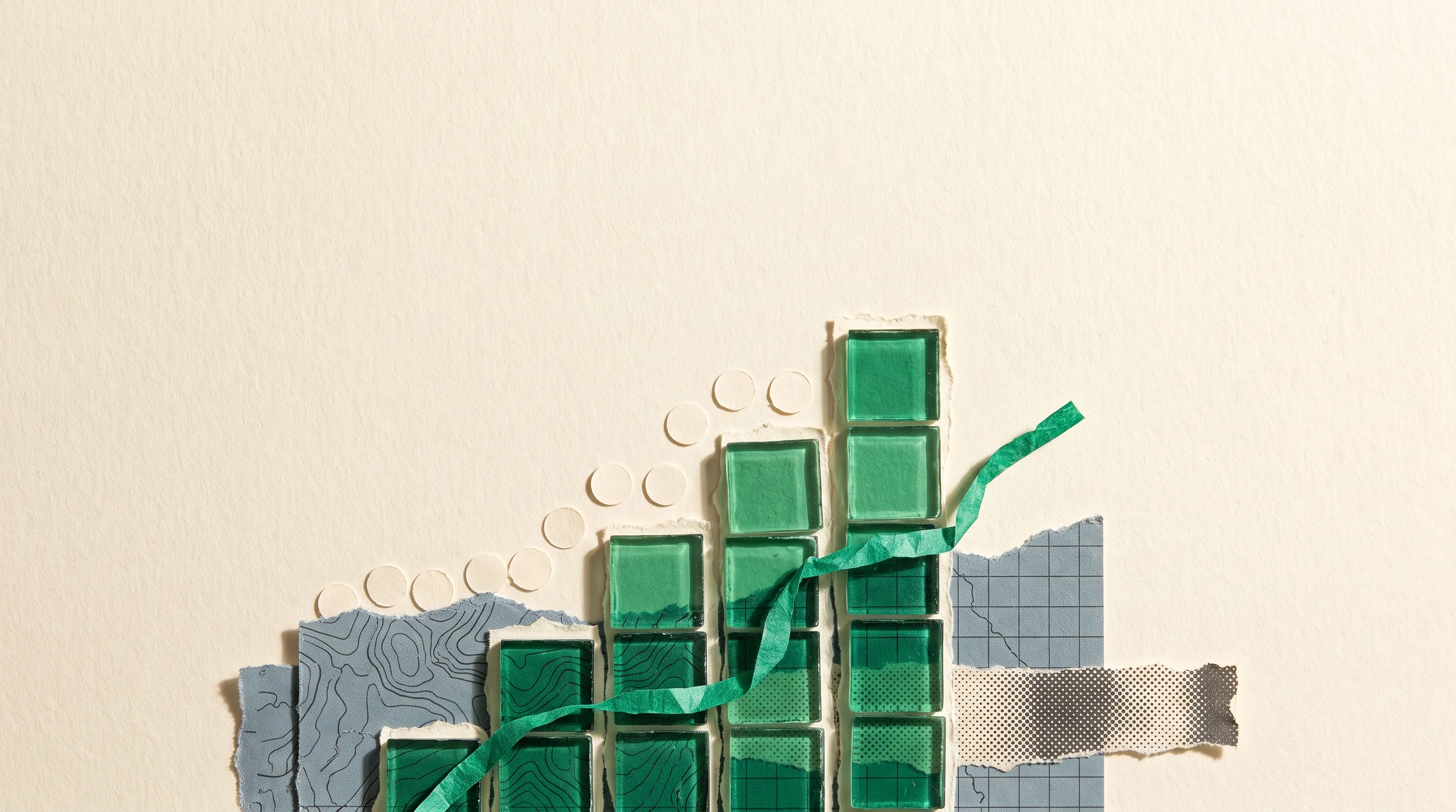 Emerald glass tiles form a bar chart over torn map fragments.