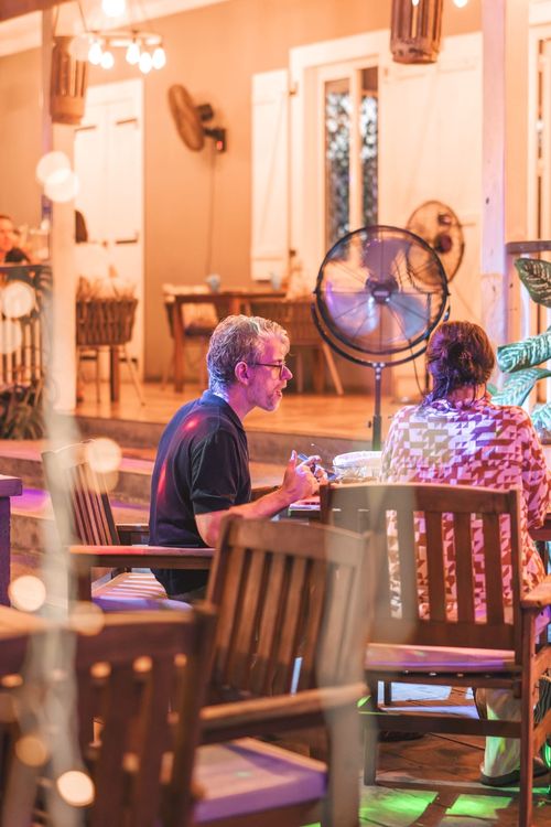 Positive young multiracial friends eating fast food and drinking beer in outdoor cafe