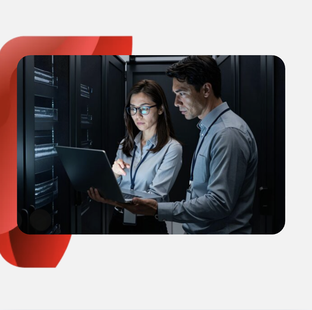 IT professionals reviewing data on a laptop in front of server hardware.