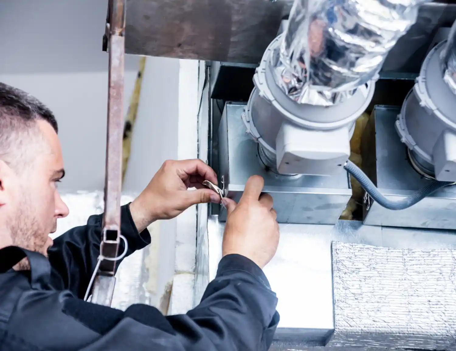 Man connecting components of an HVAC duct system.