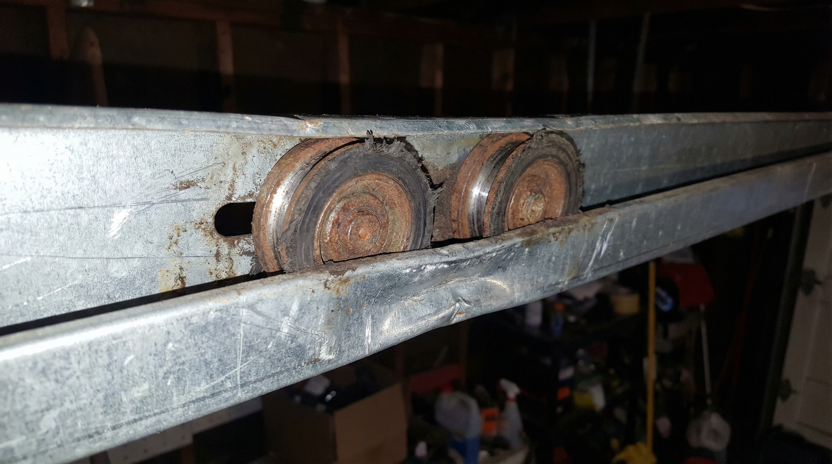 close-up view of worn garage door rollers and bent track showing visible damage