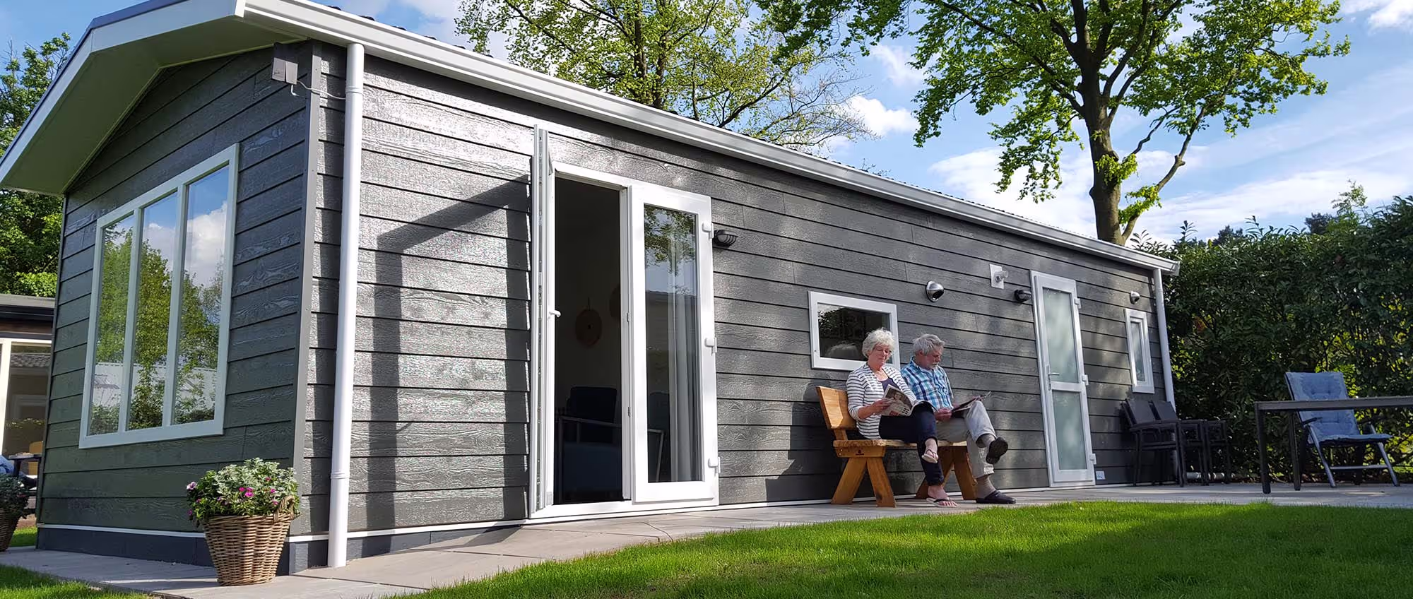 Ouder echtpaar dat op tuinstoelen voor hun moderne 