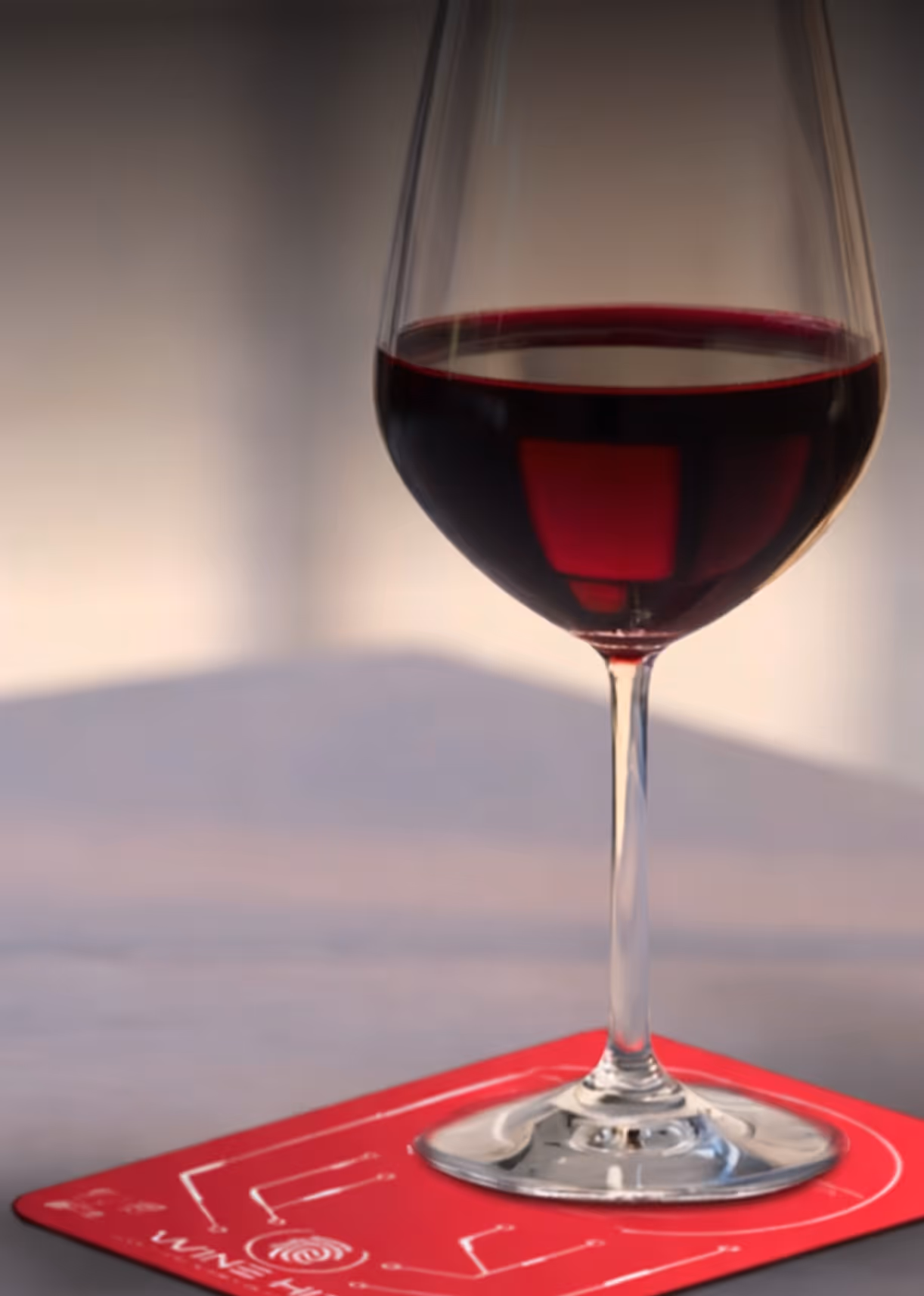 Glass of red wine on a red coaster with white circuit-like design and the word 'WINE HIT'.