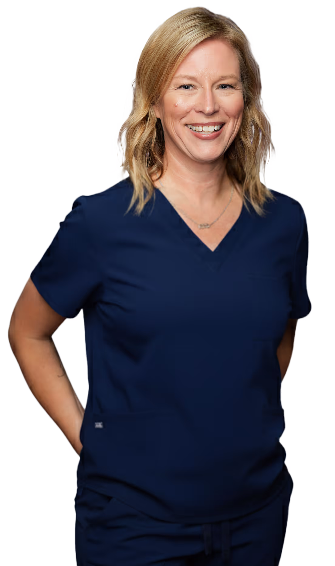 Smiling woman with blonde hair wearing navy medical scrubs with hands behind her back.