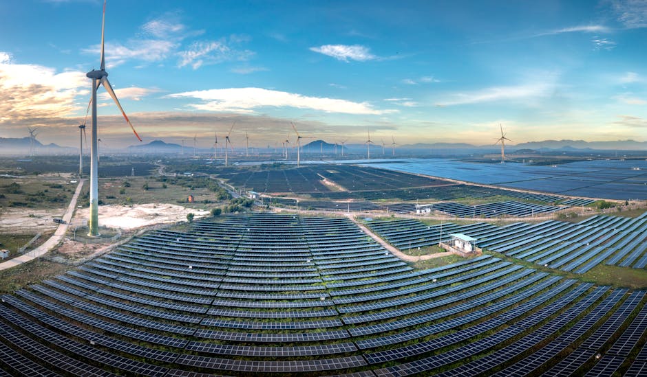 Panoramic aerial view of a renewable energy farm with solar panels and wind turbines in Vietnam at sunset.
