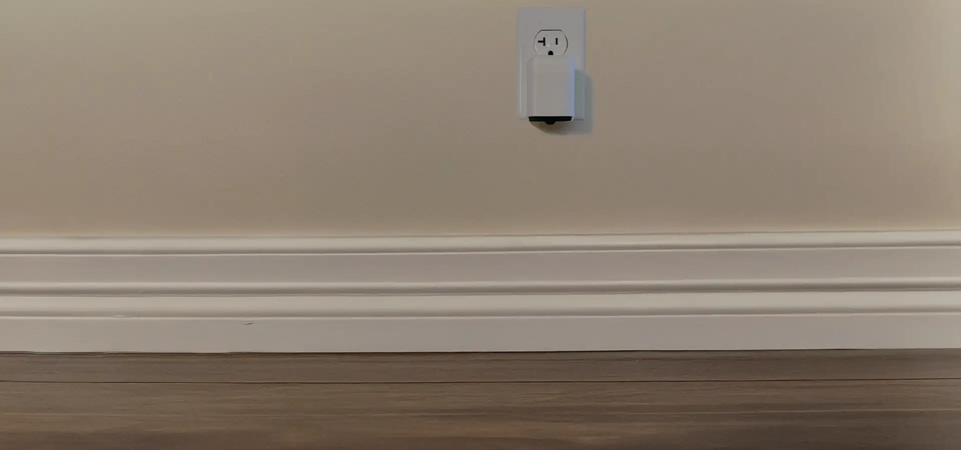 Scorpion Alert device plugged into a home wall outlet above baseboards — ultraviolet scorpion detection for your home