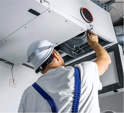 Technician in white uniform and hard hat inspecting industrial equipment