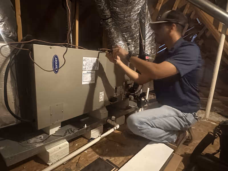 Technician repairing HVAC system in residential attic space