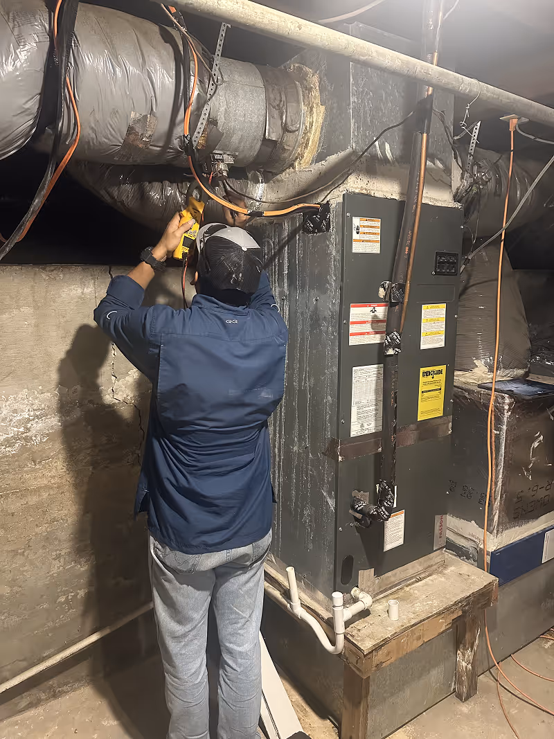 Technician inspecting HVAC system and electrical equipment in mechanical room