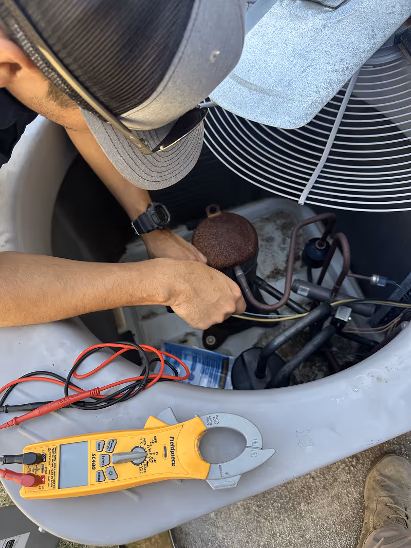 Technician using clamp meter to diagnose HVAC system electrical components