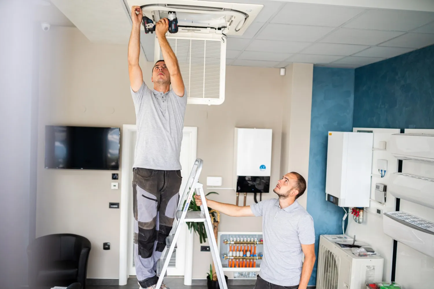 Technicians installing and checking ceiling air conditioning unit