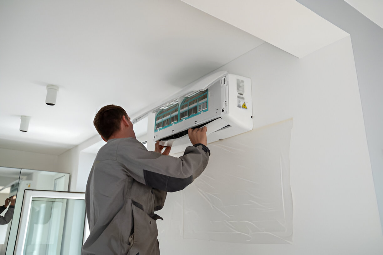Technician installing or repairing a wall-mounted air conditioning unit