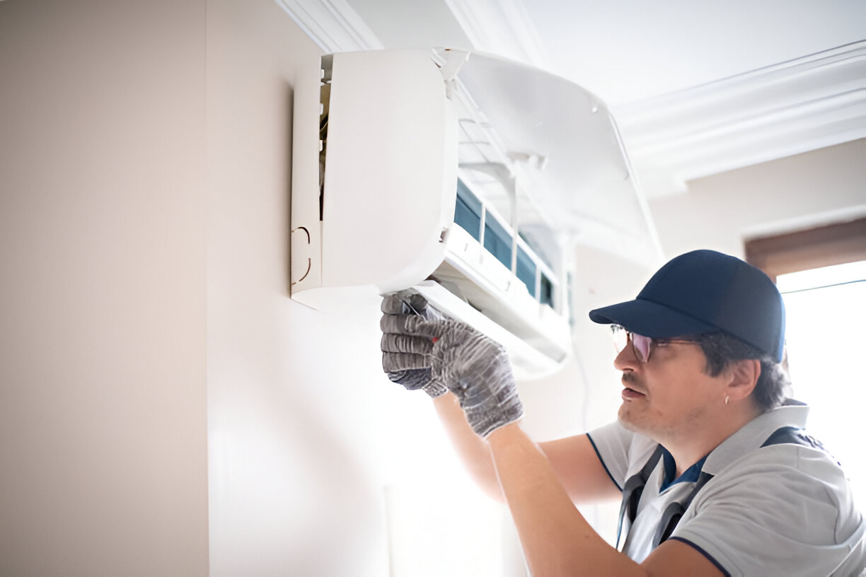 Technician installing or repairing wall-mounted air conditioning unit