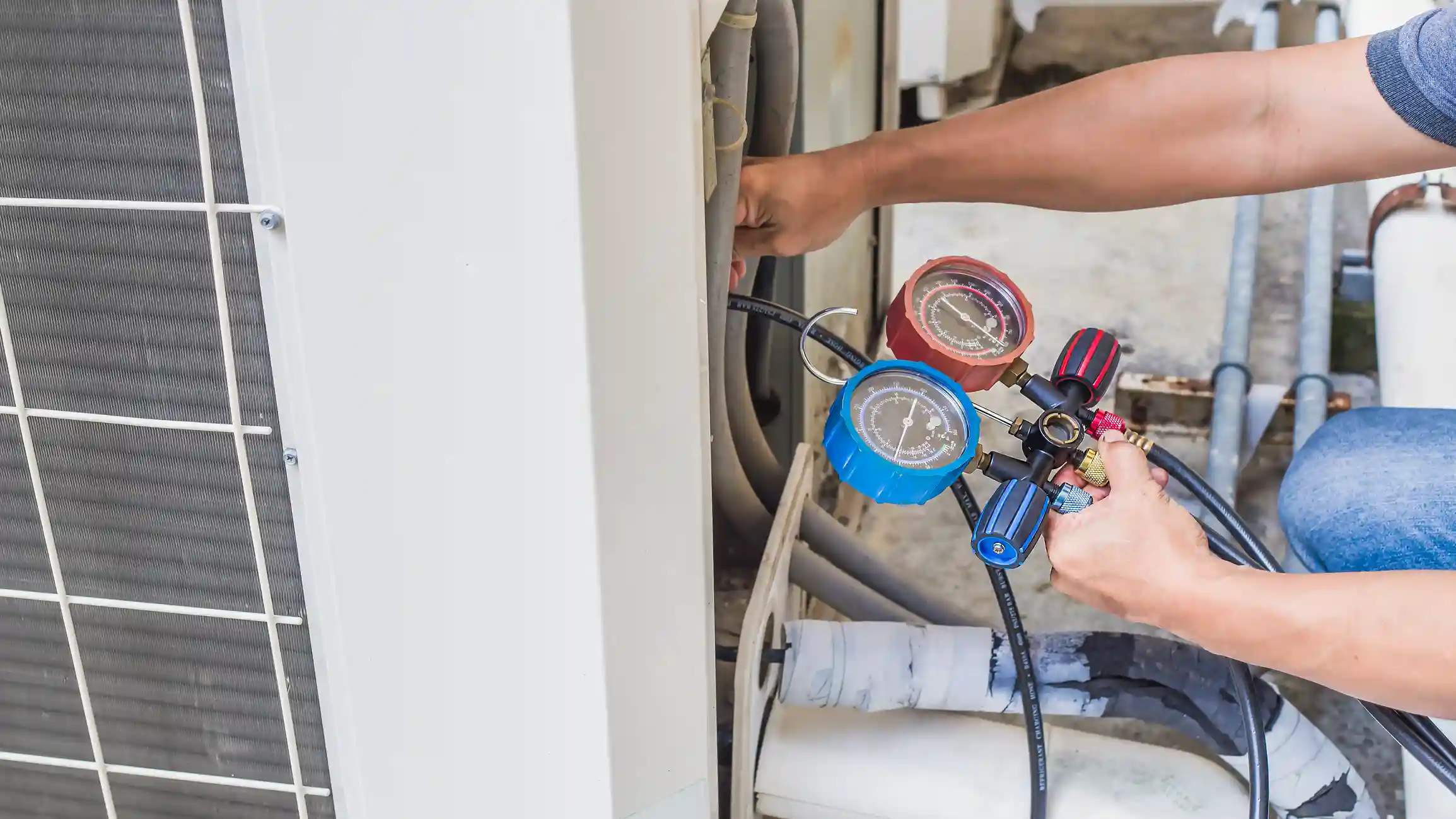 Technician checking pressure on HVAC system with blue and red gauges