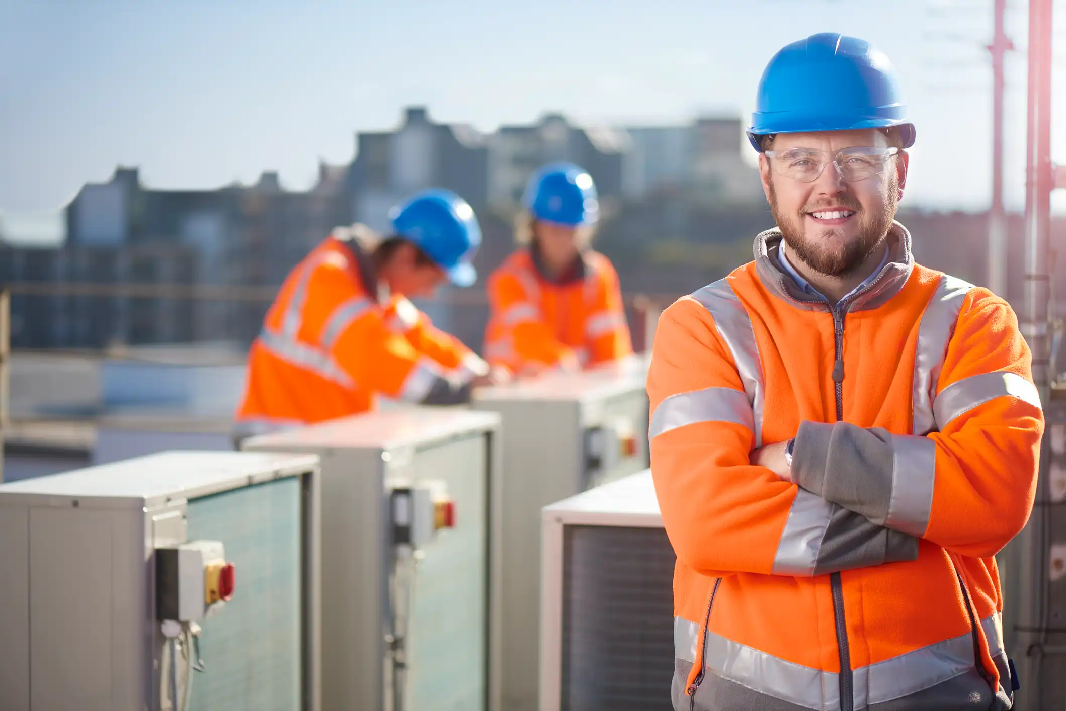 Construction workers in safety gear standing on site with industrial equipment
