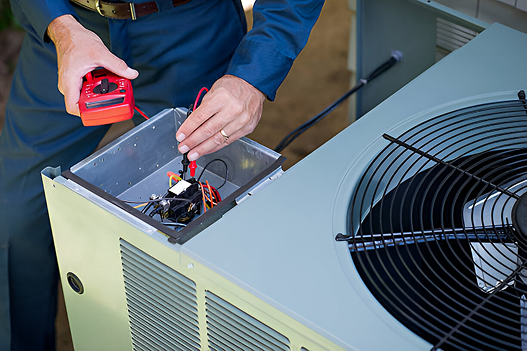 Technician repairing HVAC unit with red multimeter and open panel