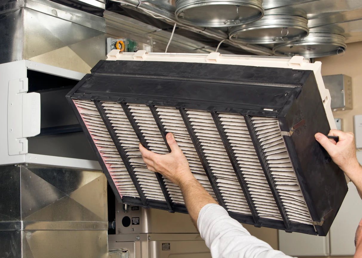 Hands removing large air filter from industrial ventilation system