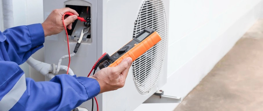 Technician using multimeter to check electrical connections on HVAC system