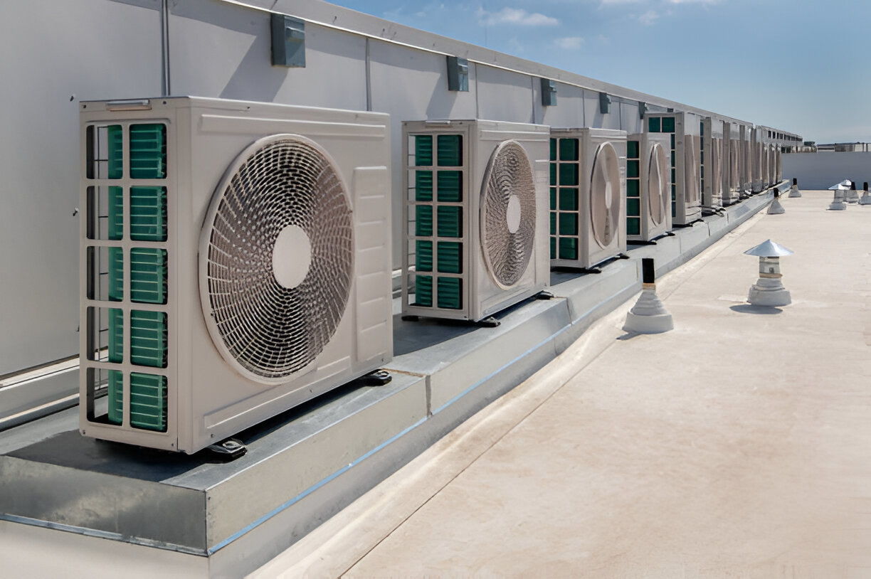 Multiple air conditioning units on a rooftop under clear blue sky