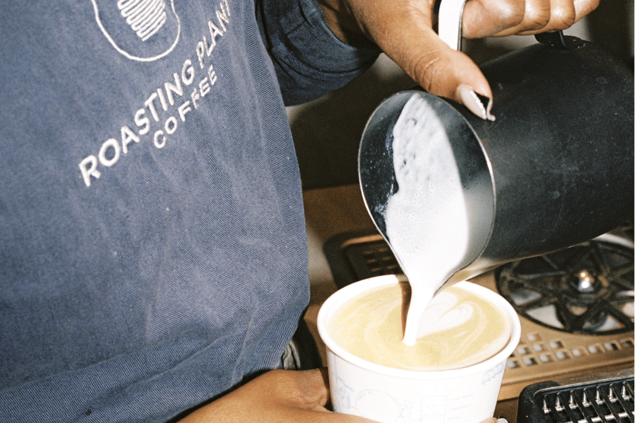 Barista pouring milk into coffee