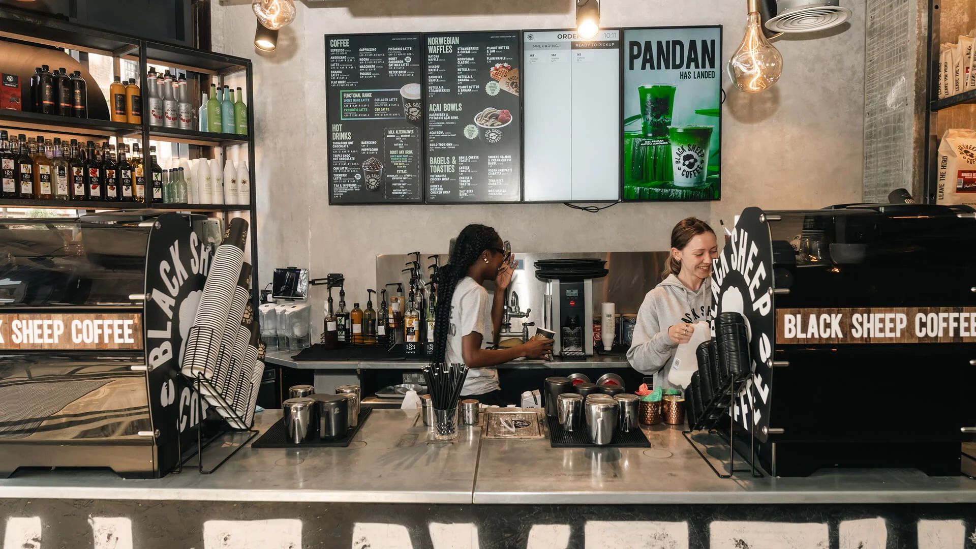 Two baristas working behind the counter and smiling