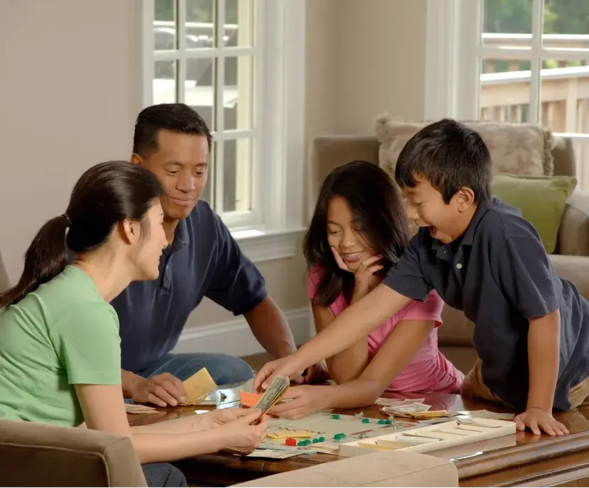 Family playing board game together at home, smiling and engaged