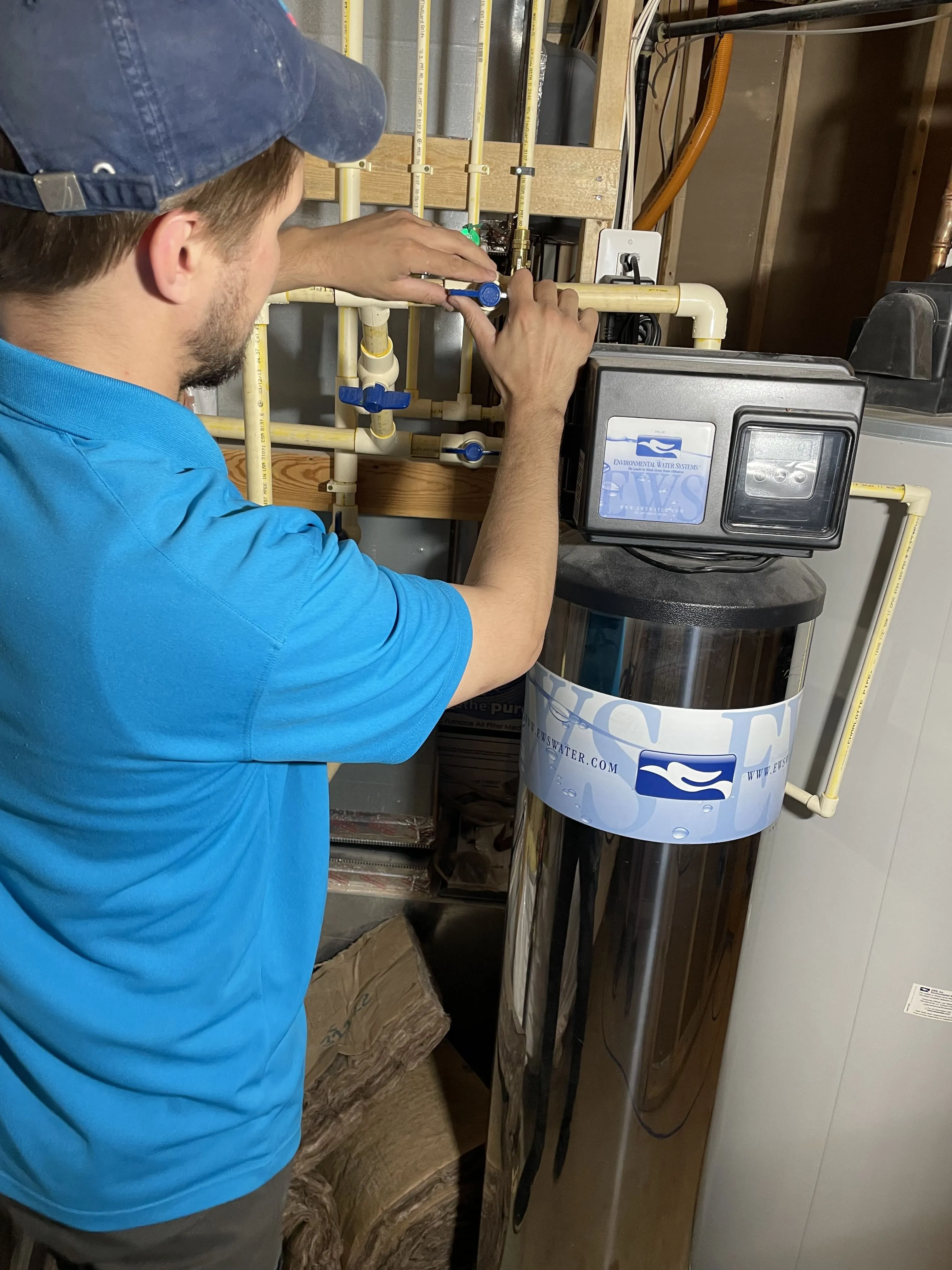 Technician adjusting water filtration system with blue valves