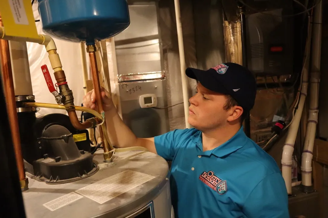 Technician in blue shirt checking water heater pipes and valves