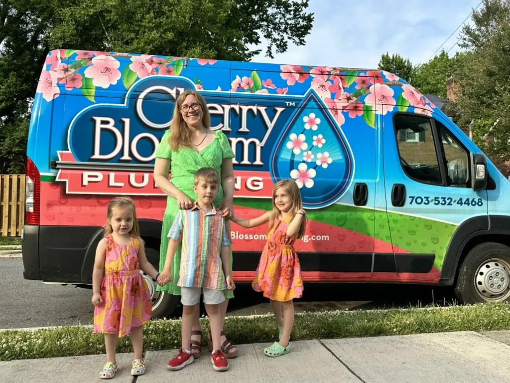 Family standing in front of colorful Cherry Blossom Plumbing van