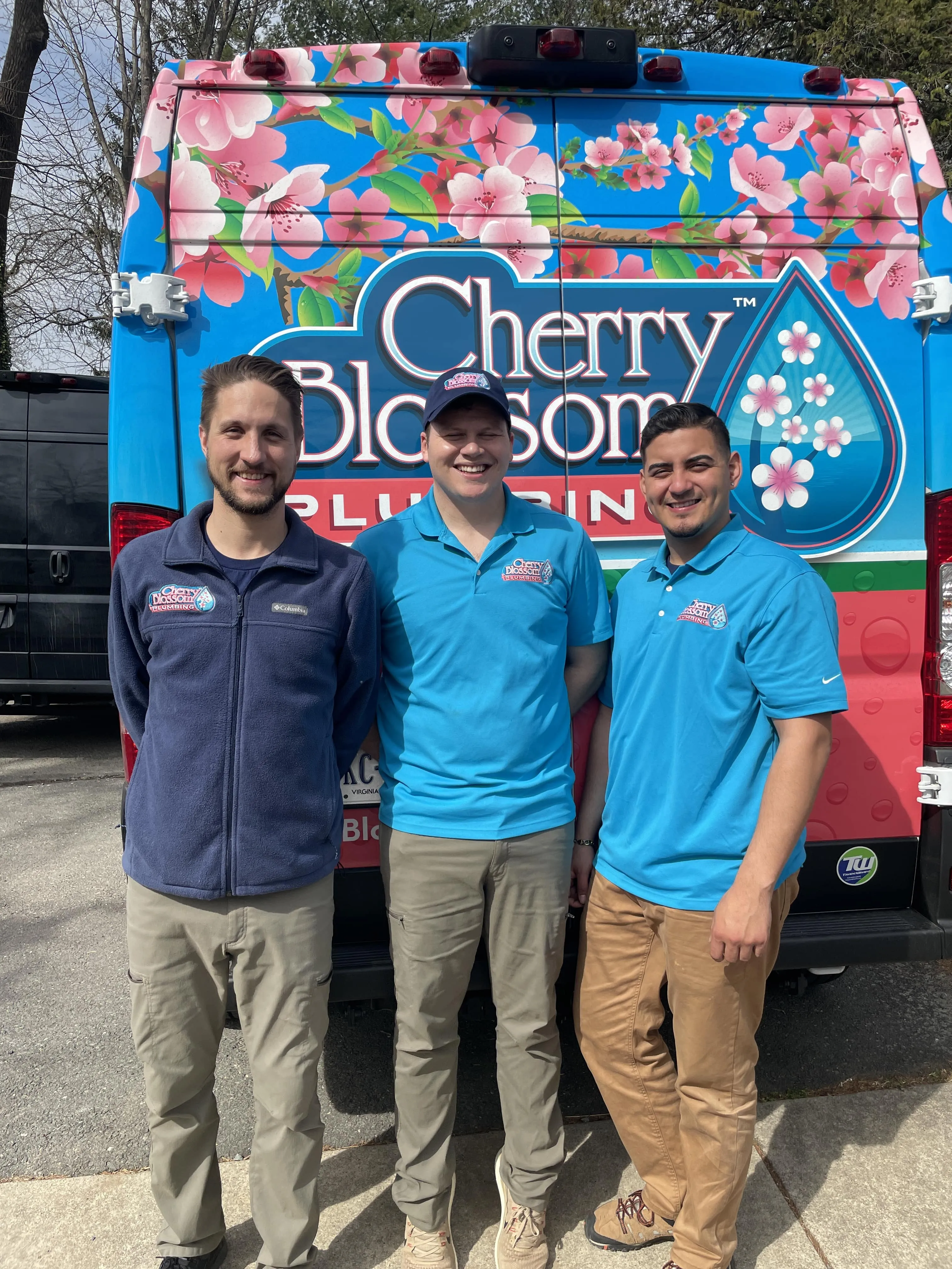 Three team members standing in front of Cherry Blossom Plus truck with floral design