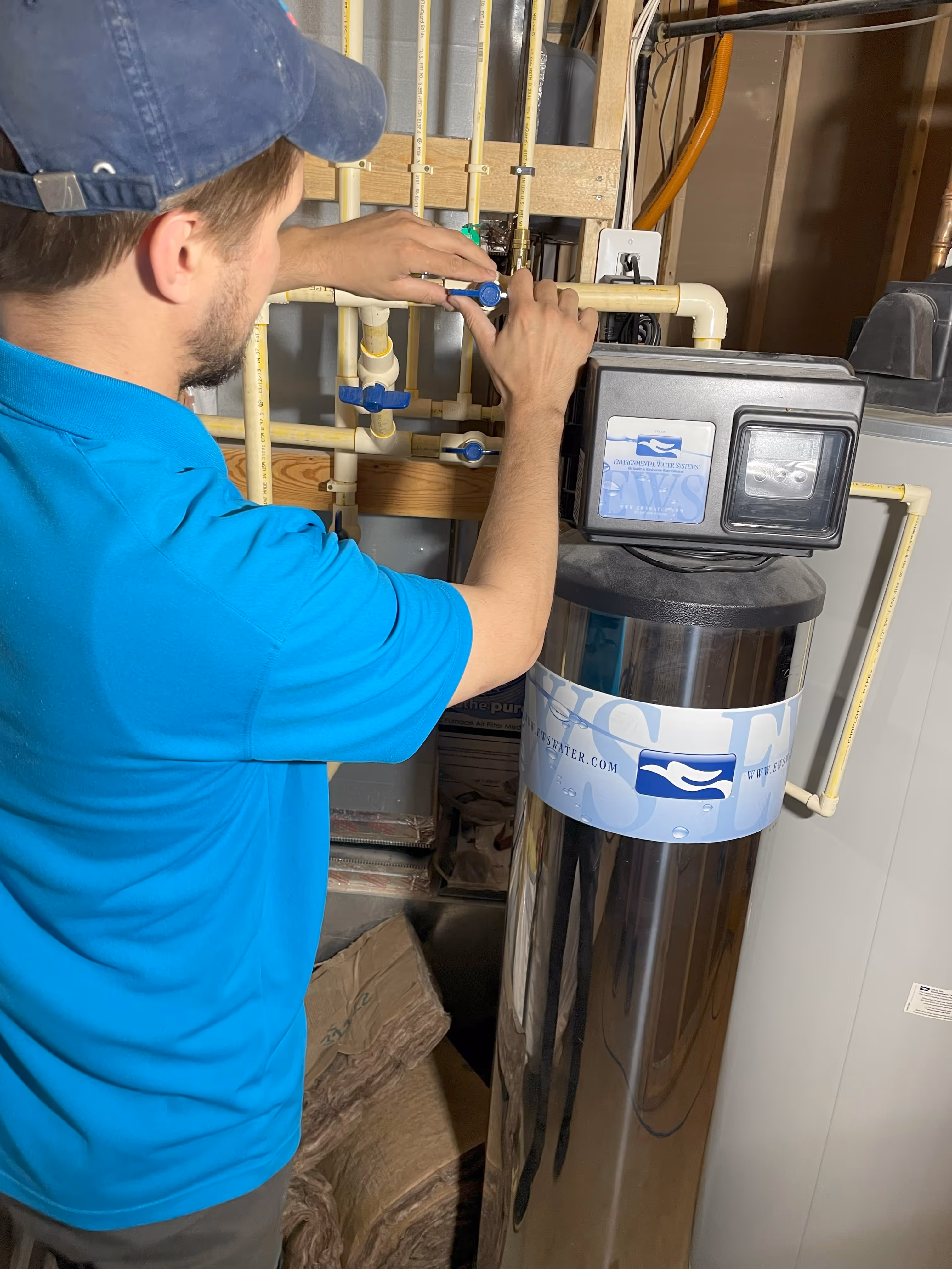 Technician adjusting water filtration system with blue valves and control panel