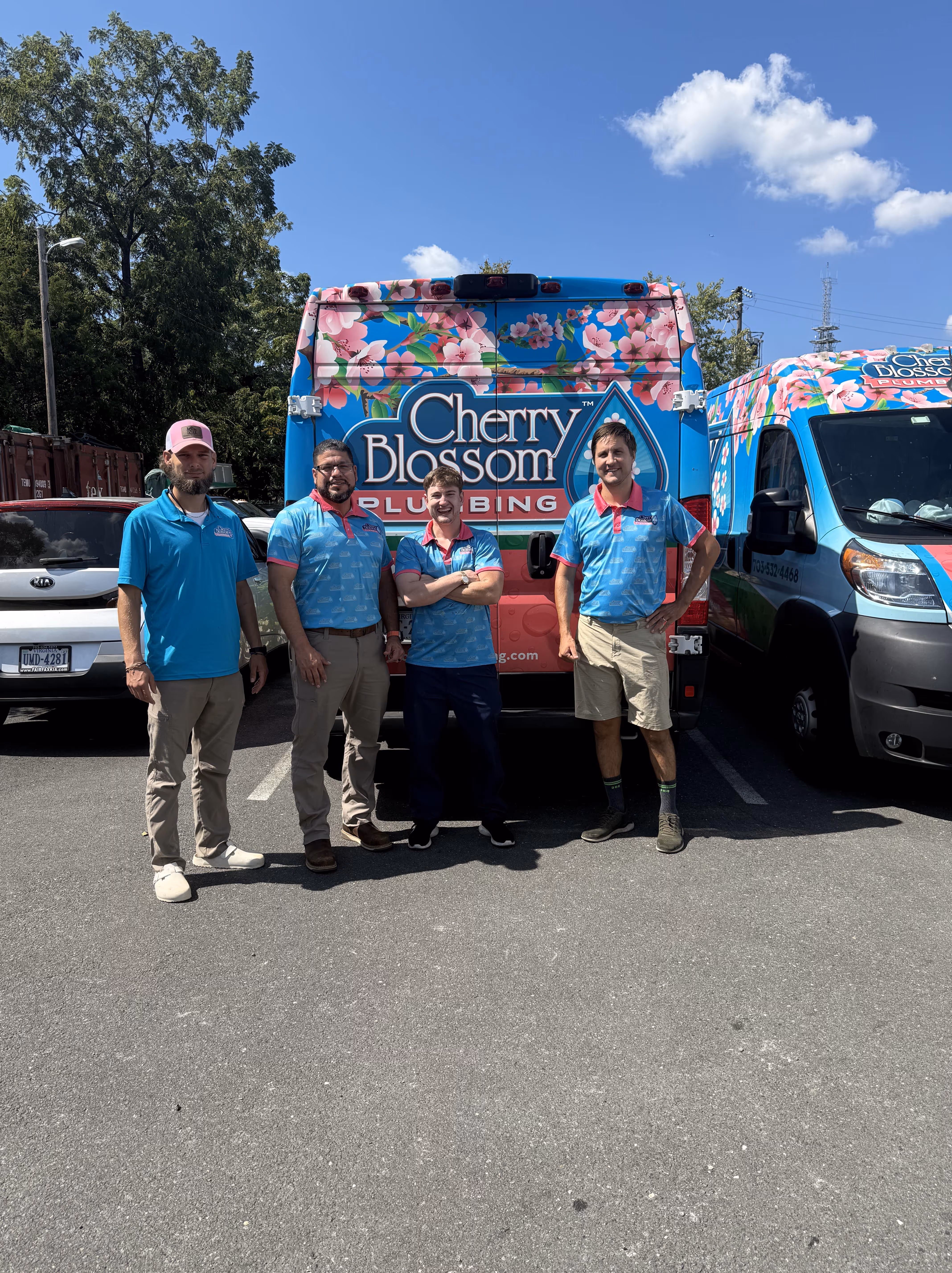 Four plumbers standing in front of colorful Cherry Blossom Plumbing van