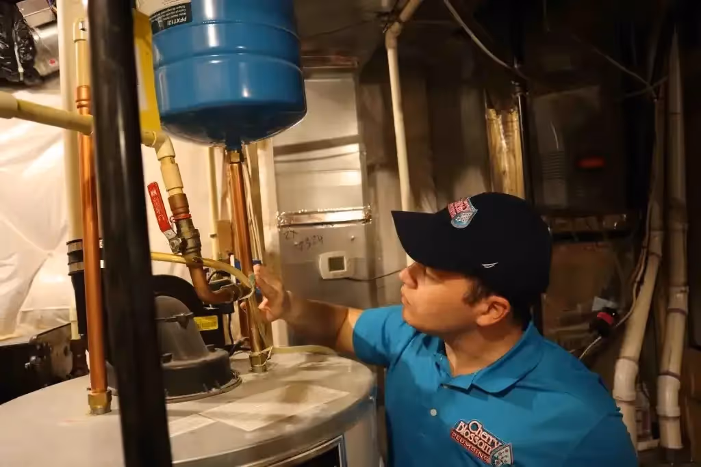 Technician in blue shirt checking water heater pipes and connections