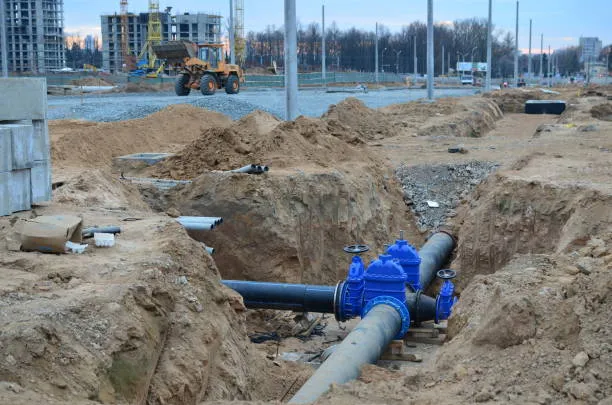 Construction site with blue water pipes, excavation, and yellow excavator